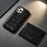 Black crocodile-patterned phone case and cardholder on a gray surface
