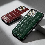 Two phone cases, one brown and one green, with a crocodile texture on a gray surface.