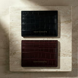 Two black and burgundy leather card holders on a marble surface with 'GENTCREATE' branding.