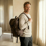 Man holding a brown backpack indoors with neutral decor
