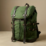 Green canvas backpack with leather straps on a beige background