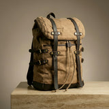 Brown canvas backpack with leather straps on a wooden surface and beige background