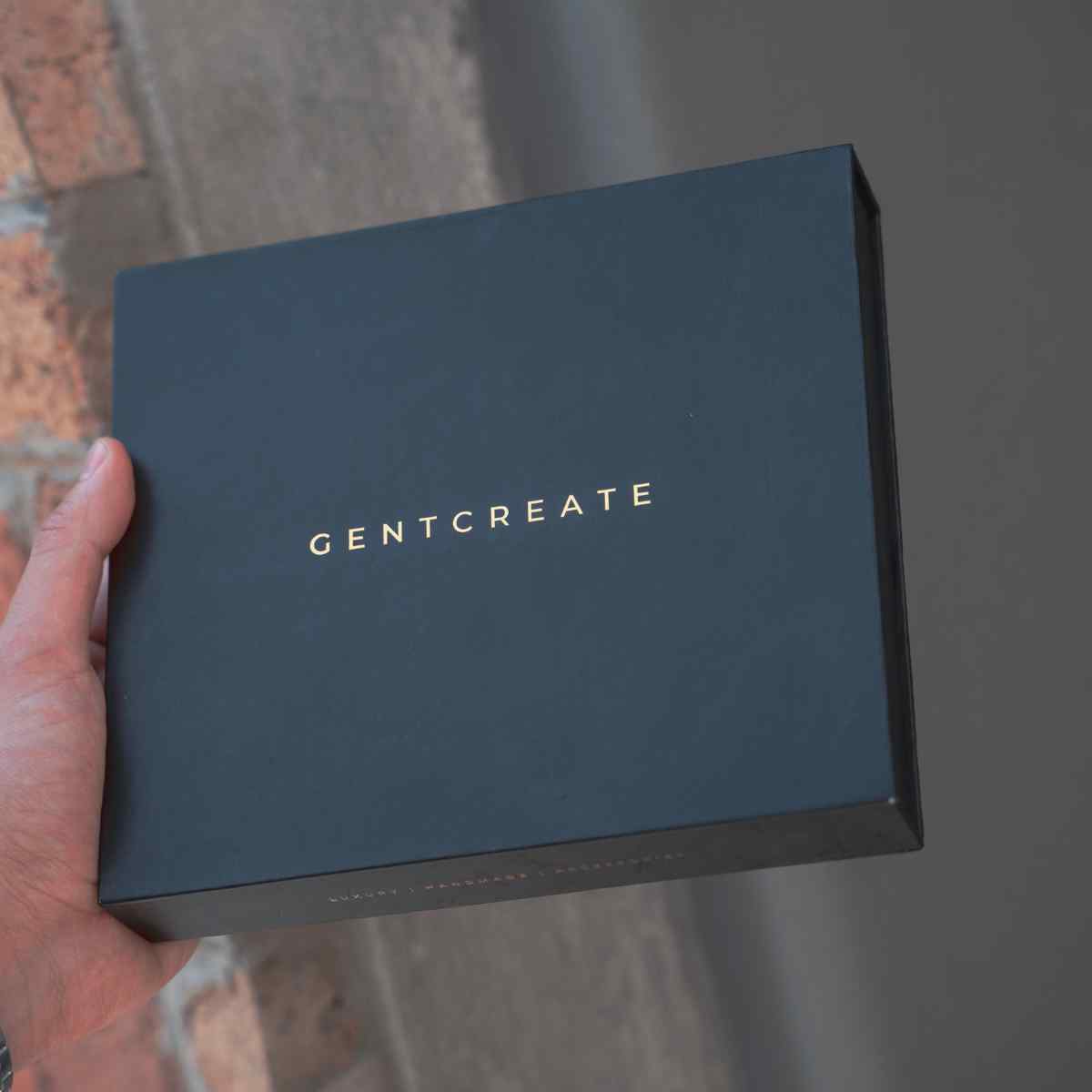 Un uomo tiene una scatola di Gentcreate con prodotti in pelle di lusso all'interno Un uomo tiene una scatola di Gentcreate con prodotti in pelle di lusso all'interno