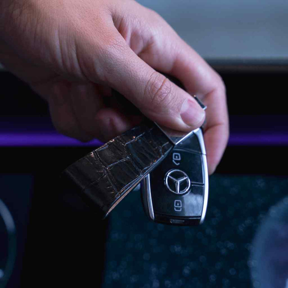 Nyckelring i krokodilläder Mannen håller en läder nyckelring från Gentcreate med en Mercedes-nyckel