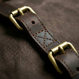 Close-up of a brown leather strap with brass buckles on a textured brown background