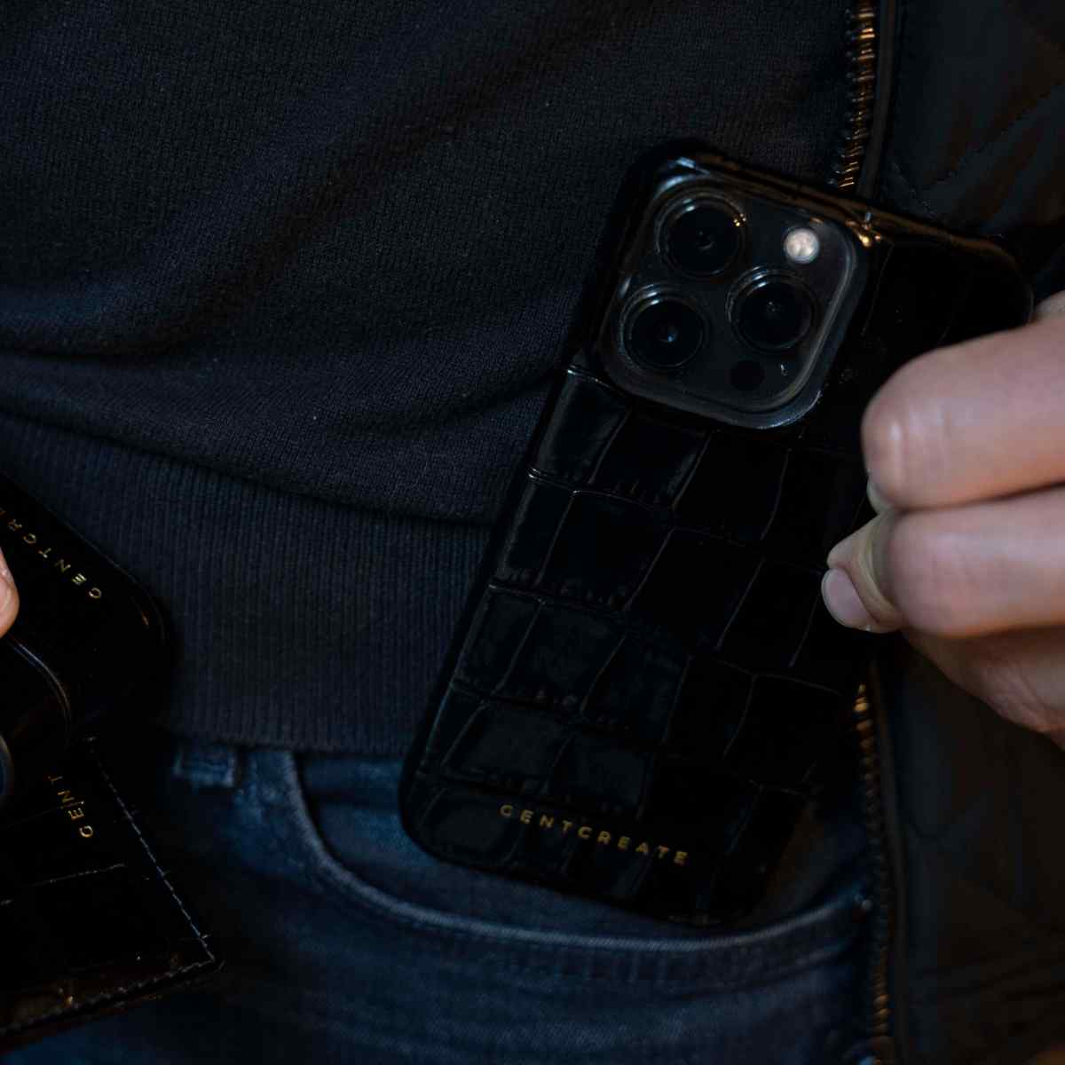 The man is putting a black Glossy leather iPhone 11 Case By gentcreate into the pocket of his jeans