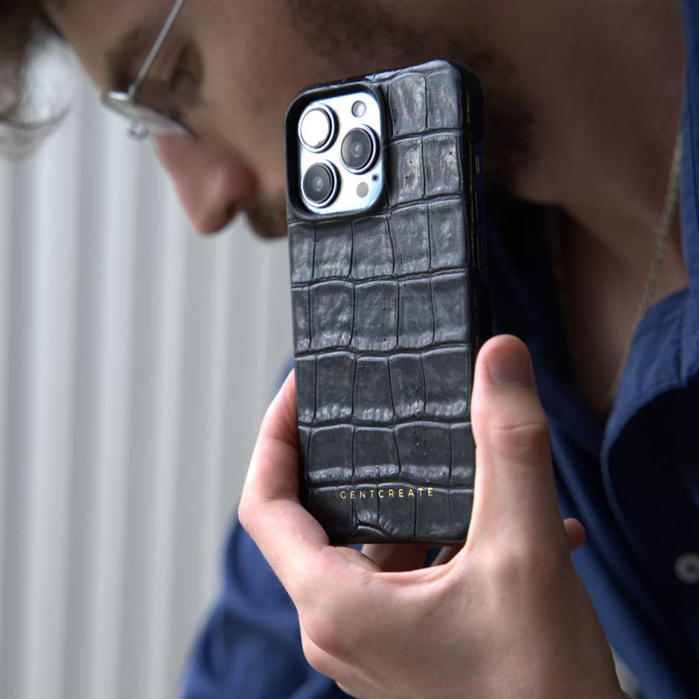 The man is holding his black crocodile iPhone case by the luxury brand Gentcreate.