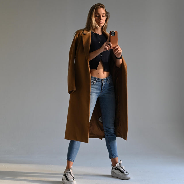 한 소녀가 젠트크리에이트 브랜드의 갈색 사피아노 가죽 전화 케이스를 들고 있습니다.