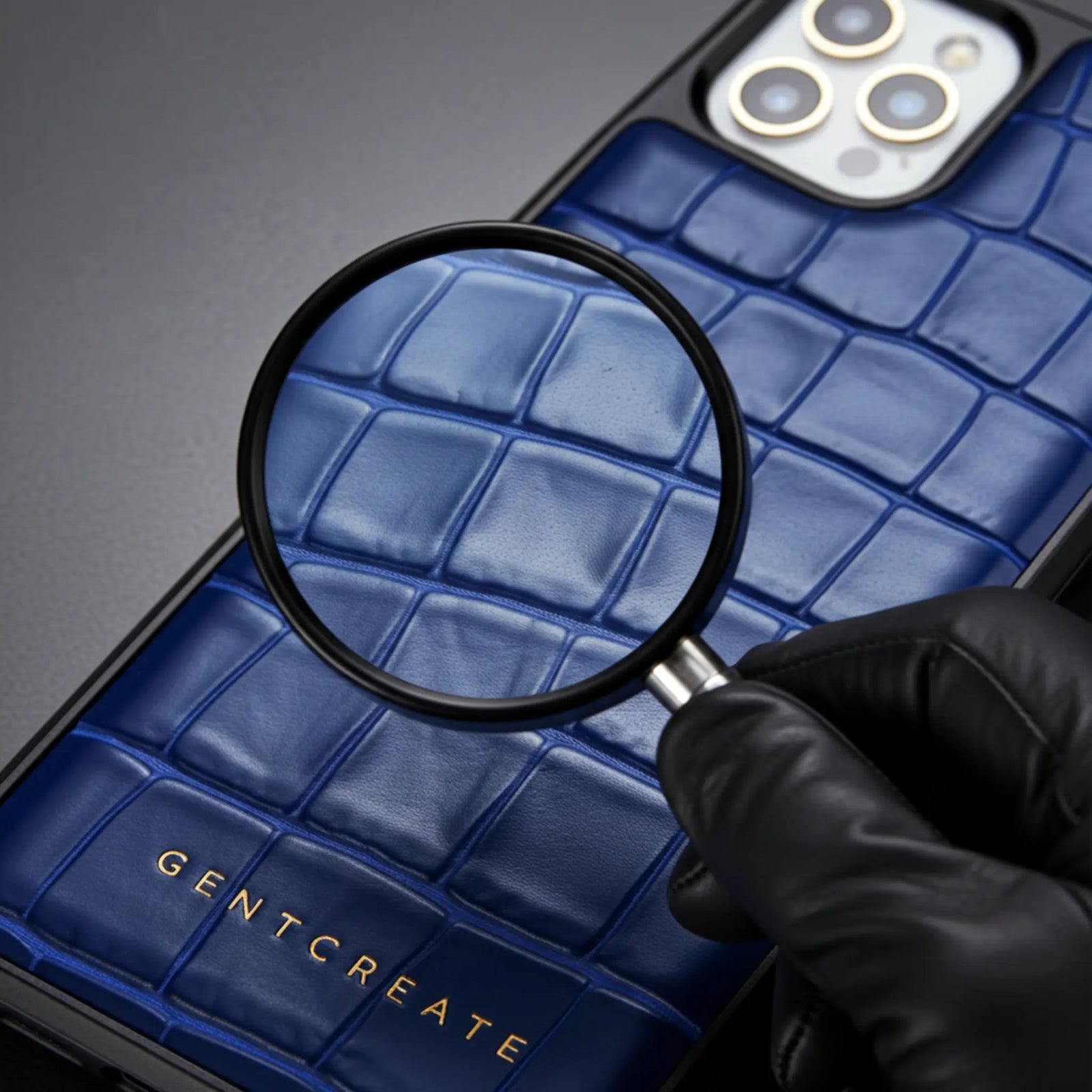 Blue textured crocodile leather iPhone 17 case with magnifying glass and 'GENTCREATE' branding