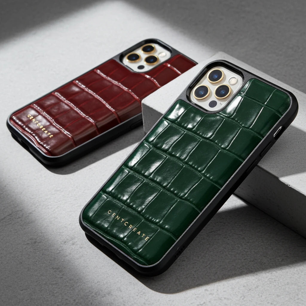 Two phone cases, one brown and one green, with a crocodile texture on a gray surface.