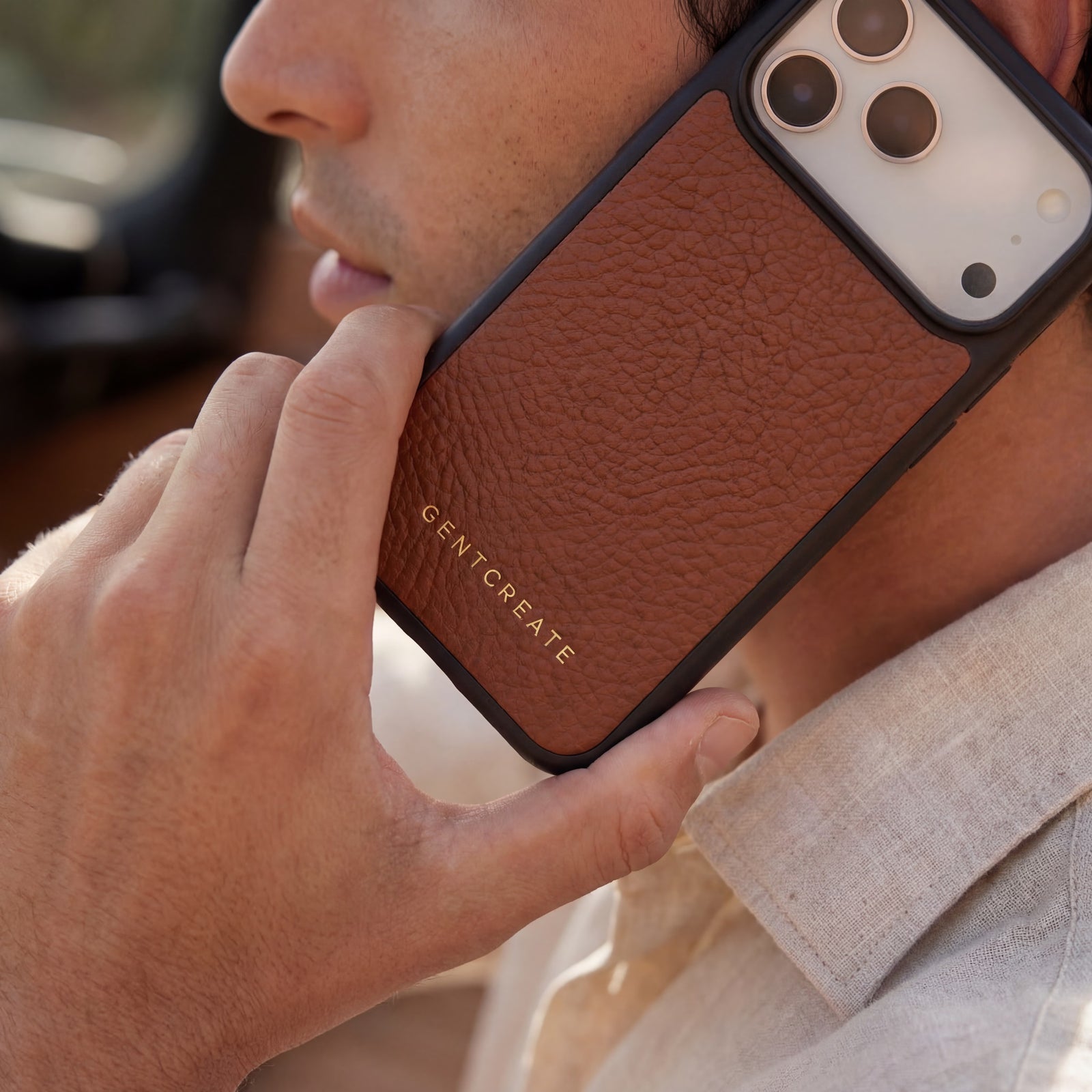 Man holding a brown iPhone 17 Pro max Italian full-grain pebble leather case with old money brand GENTCREATE logo close up texture Italian calfskin