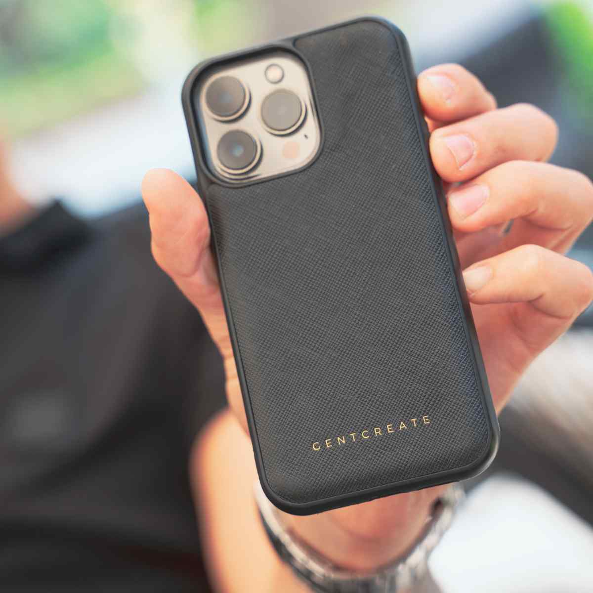 A man is holding an iPhone 11 case in a Saffiano Black Leather Case by Gentcreate