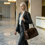 Woman in a suit walking through a marble hallway with a GENTCREATE brown crocodile leather bag.