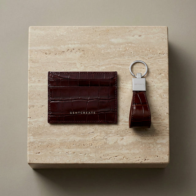 Burgundy leather cardholder and crocodile burgundy leather keychain on a beige stone surface