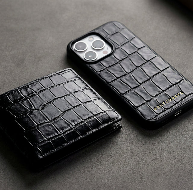 Black crocodile-patterned leather iPhone case and crocodile embossed leather wallet by luxury fashion brand GENTCREATE on a gray surface