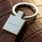Burgundy crocodile leather keychain with GENTCREATE branding on a burgundy crocodile embossed surface