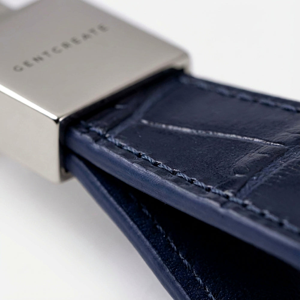 Close-up of a blue crocodile leather keychain with stitching detail, branded 'GENTCREATE.