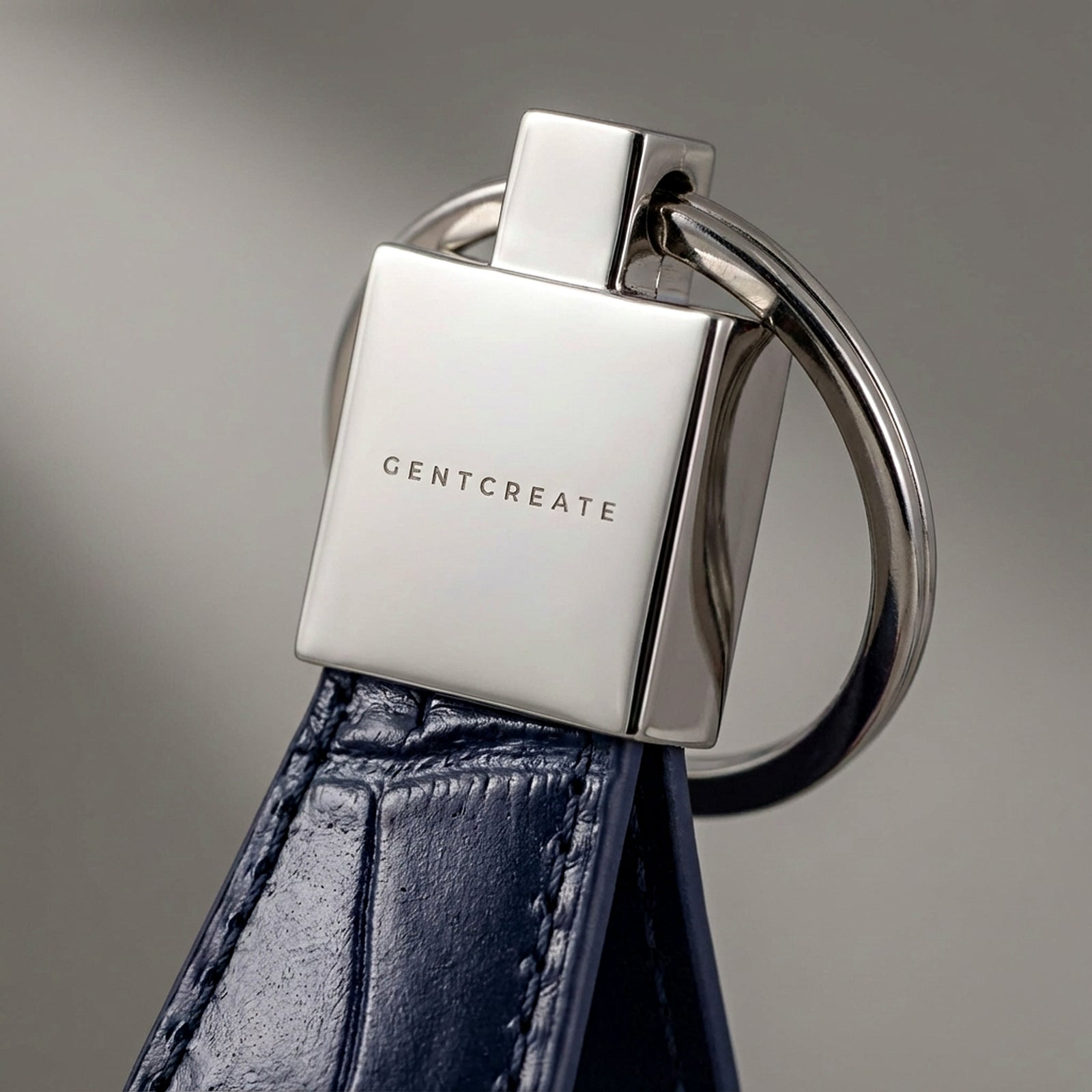Metallic keychain with 'GENTCREATE' branding on a leather strap against a gray background
