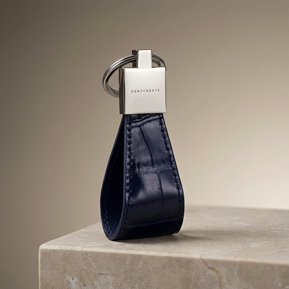 Blue leather keychain with silver tag on a beige surface