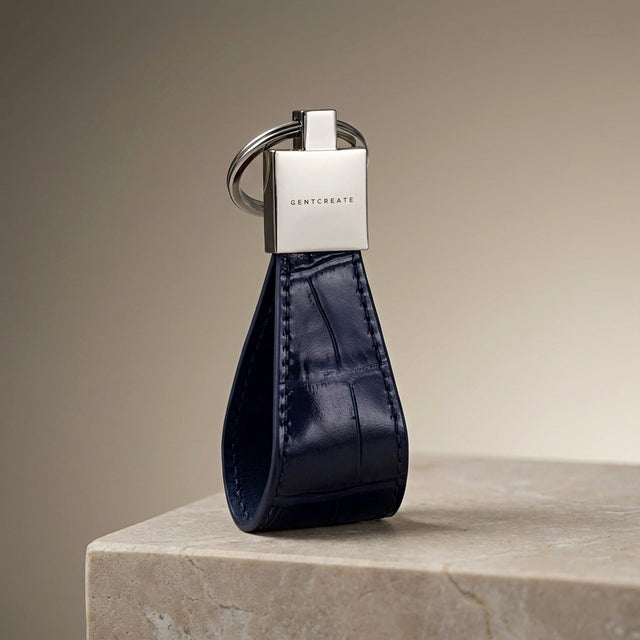 Blue leather keychain with silver tag on a beige surface