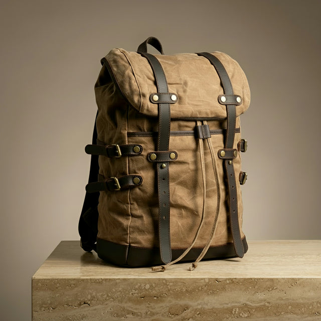 Brown canvas backpack with leather straps on a wooden surface and beige background