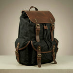 Black canvas and leather backpack with brown leather straps on a neutral background