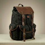 Black canvas and leather backpack with brown leather straps on a neutral background