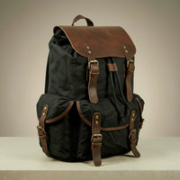 Black canvas and leather backpack with brown leather straps on a neutral background