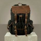 Black canvas and leather backpack with brown leather straps on a neutral background
