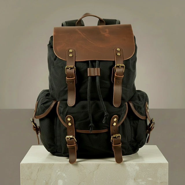 Black canvas and leather backpack with brown leather straps on a neutral background