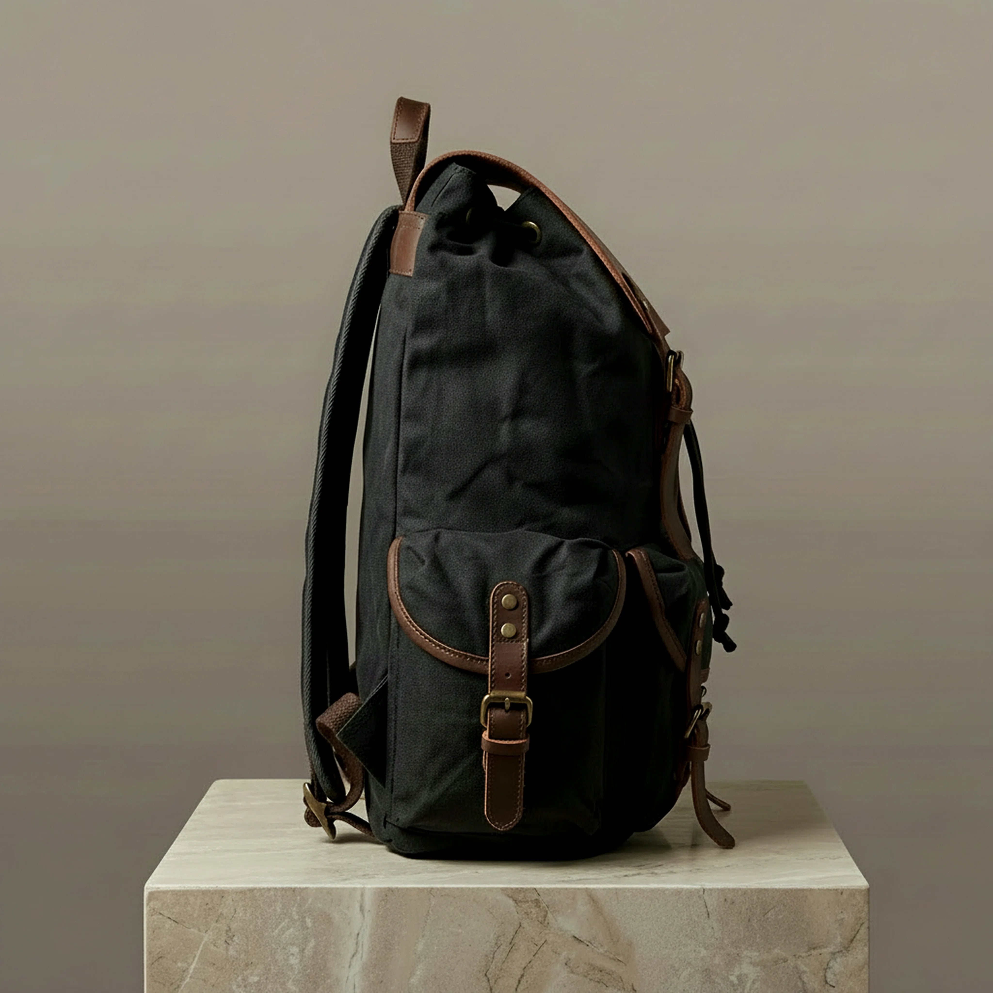 Black backpack with brown leather straps on a neutral background