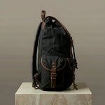 Black backpack with brown leather straps on a neutral background