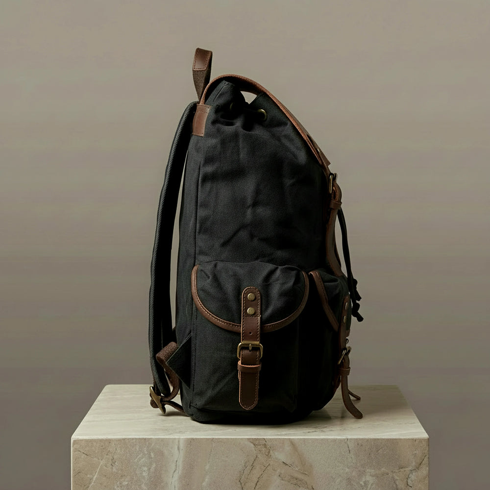 Black backpack with brown leather straps on a neutral background