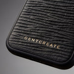 Close-up of a black Italian calfskin textured iPhone wave leather pattern case with 'GENTCREATE branding on a gray background