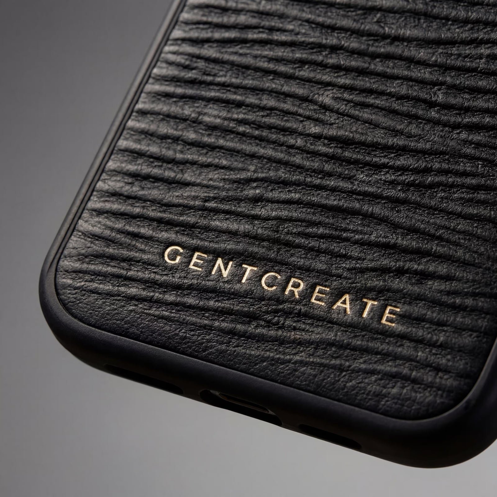 Close-up of a black Italian calfskin textured iPhone wave leather pattern case with 'GENTCREATE branding on a gray background