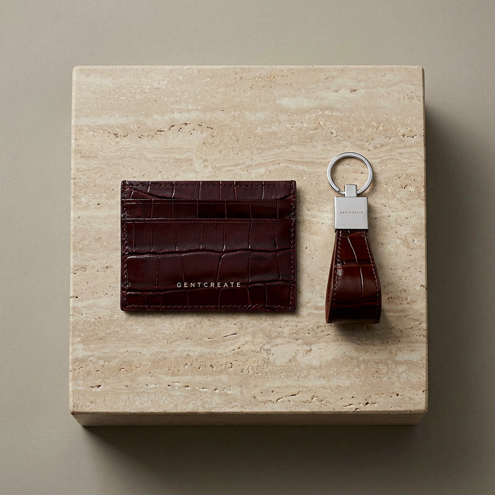 Burgundy leather cardholder and crocodile burgundy leather keychain on a beige stone surface