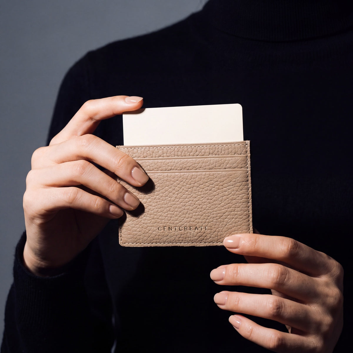 Close-up of hands holding a beige pebble leather card holder by GENTCREATE with a card in the top slot