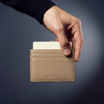 Hand holding a beige pebble leather card holder by GENTCREATE, a card rising from the top slot
