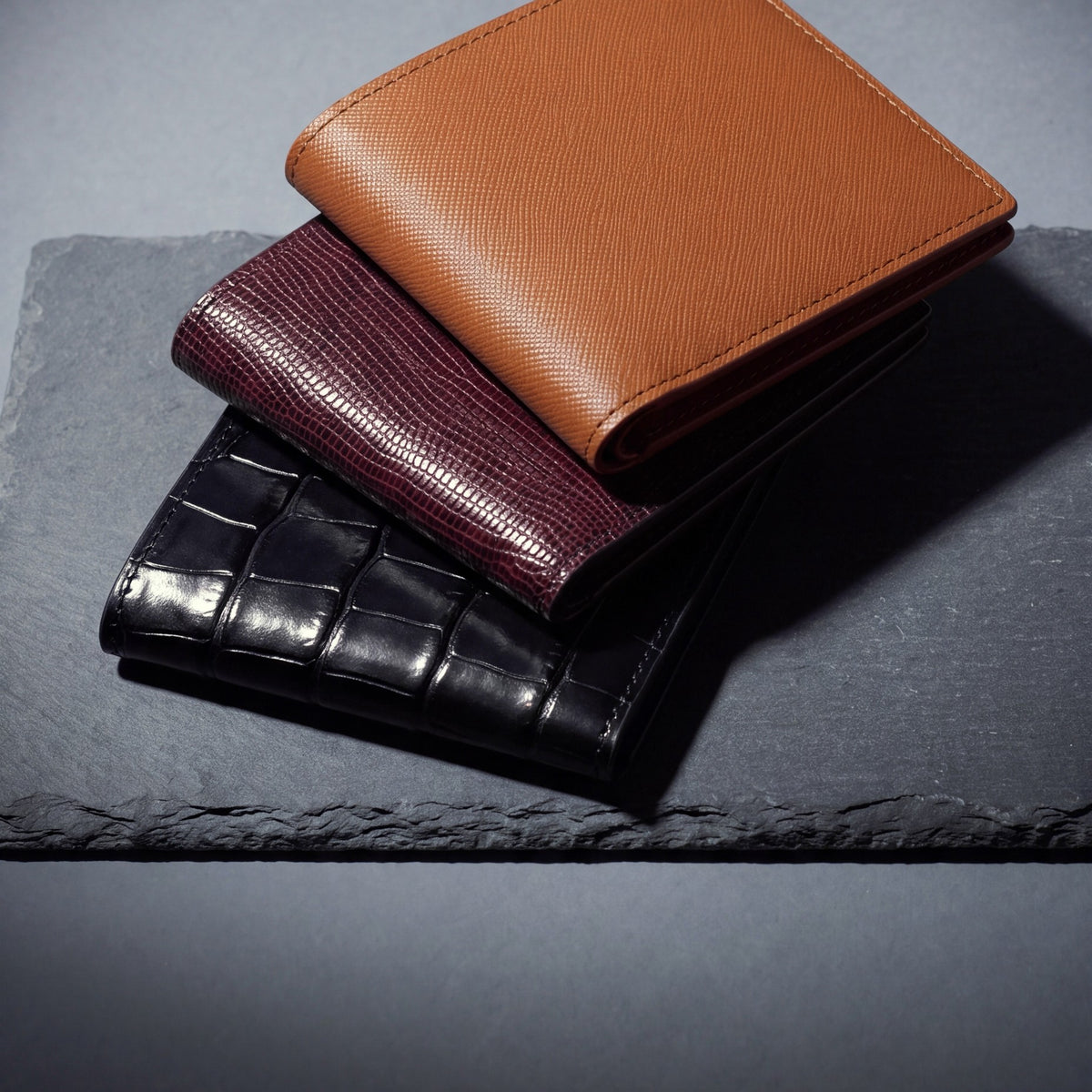 Bifold wallets by GENTCREATE in crocodile-embossed, lizard and Saffiano leather, stacked