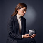 Woman seated, holding a black crocodile-embossed leather bifold wallet by GENTCREATE