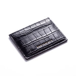Black crocodile-embossed leather card holder by GENTCREATE lying at an angle on white