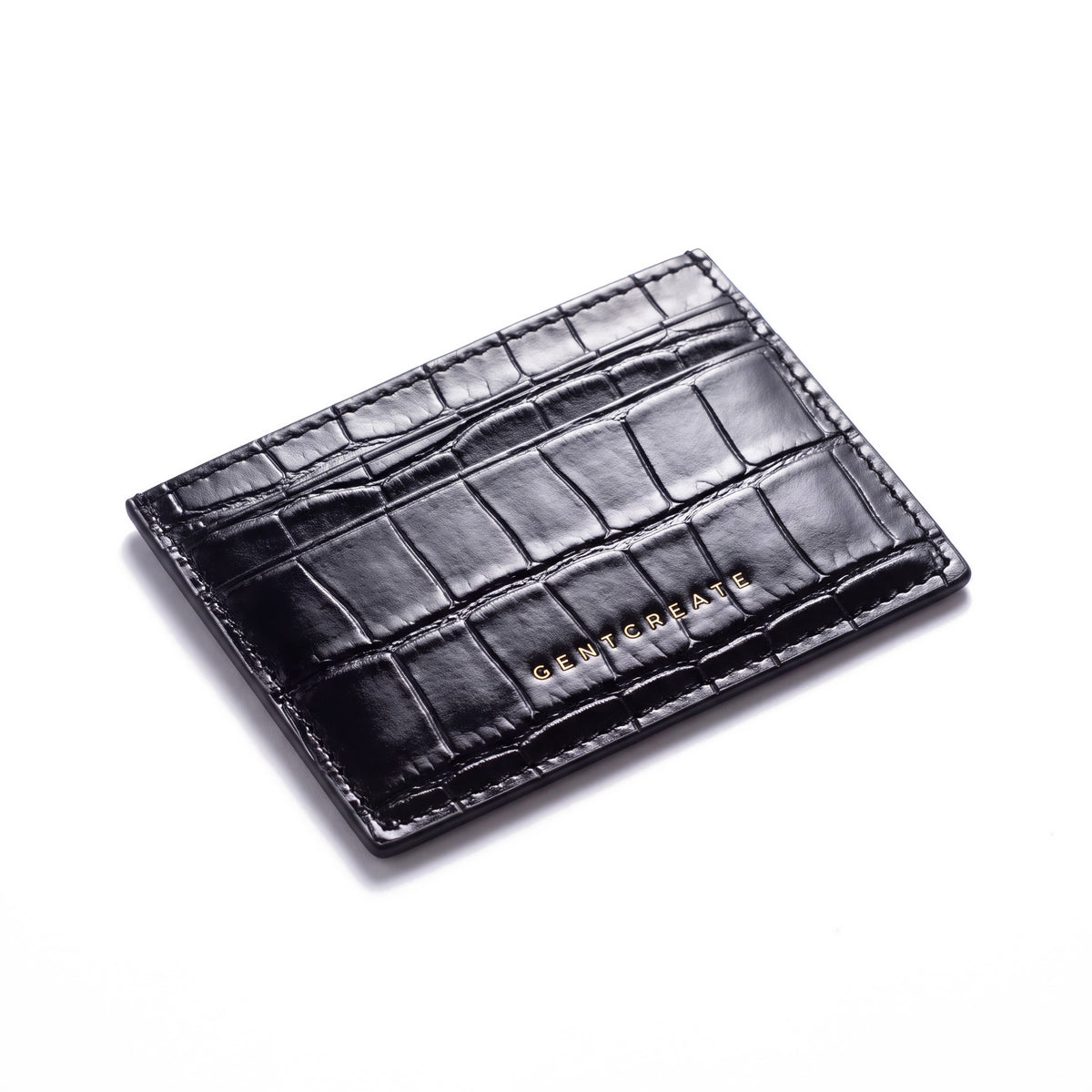 Black crocodile-embossed leather card holder by GENTCREATE lying at an angle on white