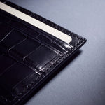Close-up of the grain and edge of a black crocodile-embossed leather card holder by GENTCREATE