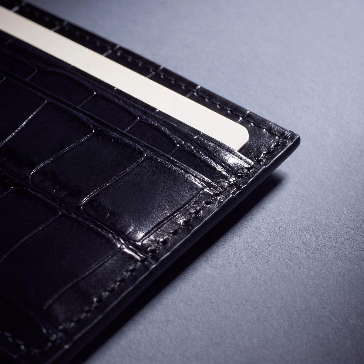 Close-up of the grain and edge of a black crocodile-embossed leather card holder by GENTCREATE