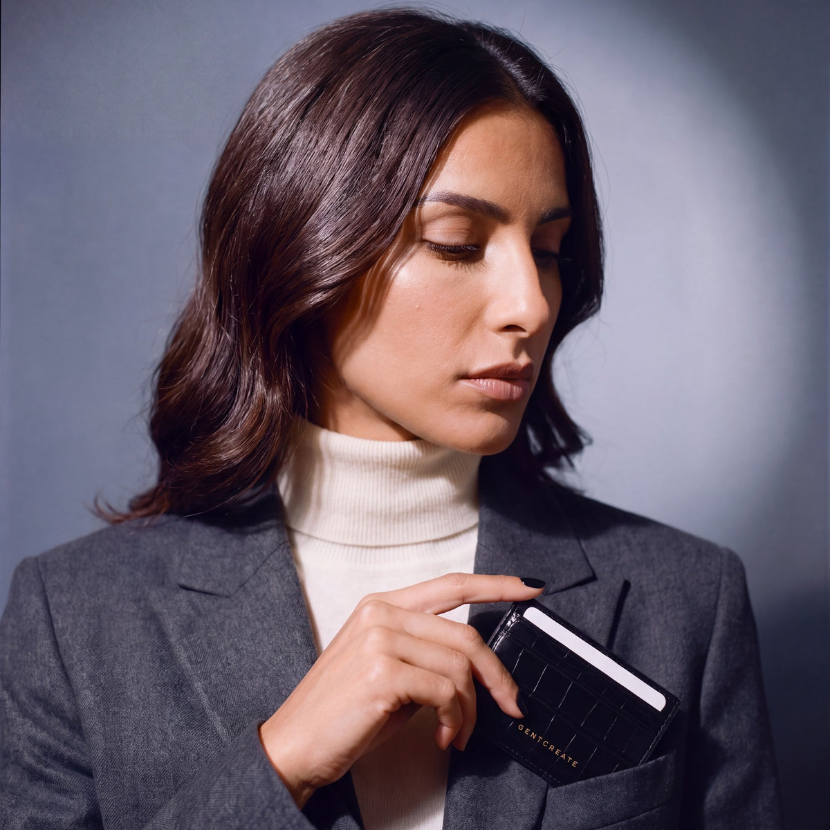 Woman slipping a black crocodile-embossed leather card holder by GENTCREATE into a blazer chest pocket