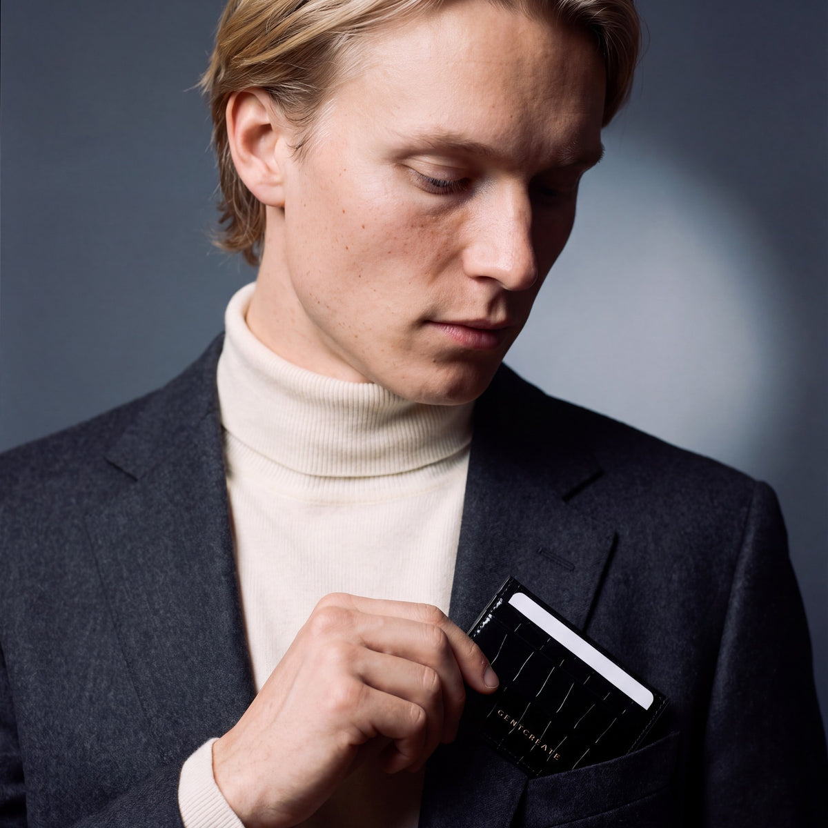 Man slipping a black crocodile-embossed leather card holder by GENTCREATE into a blazer chest pocket