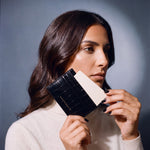 Woman holding a slim black crocodile-embossed leather card holder by GENTCREATE and drawing out a card