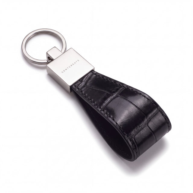 Black crocodile-embossed leather keychain by GENTCREATE lying at an angle on white