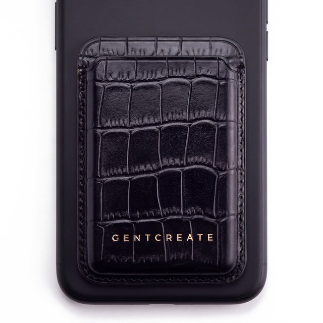 Black crocodile-embossed leather magnetic card wallet by GENTCREATE on the back of a phone, on white