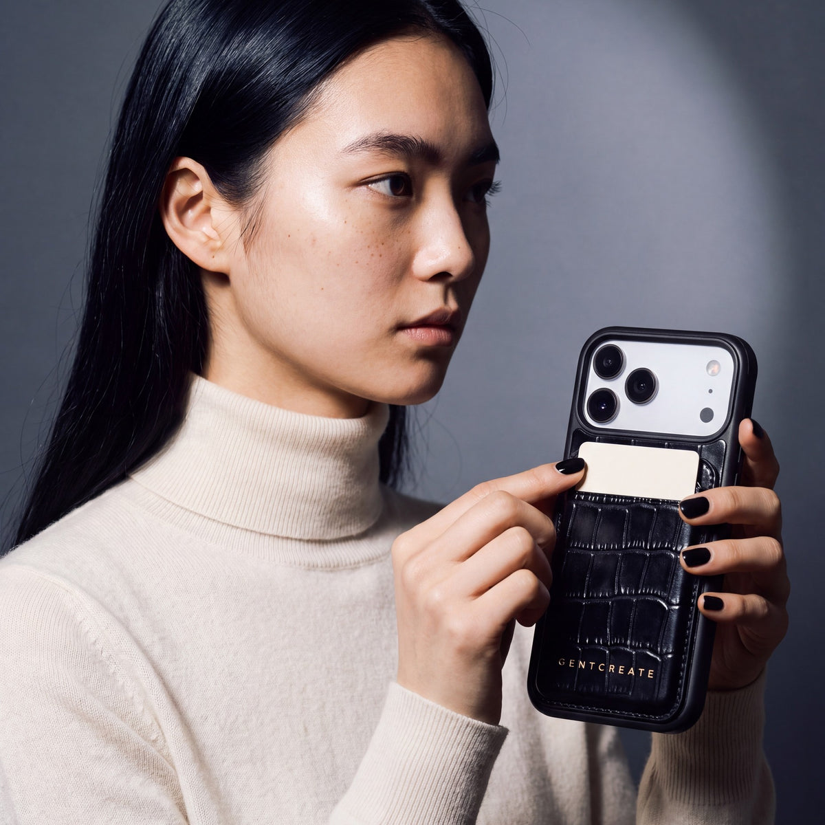 Woman holding a phone with a black crocodile-embossed leather MagSafe wallet by GENTCREATE on the back